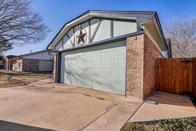 garage with concrete driveway and fence