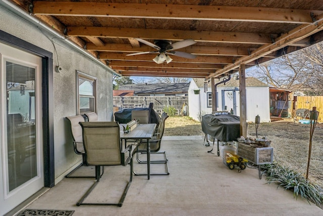 view of patio with an outbuilding, ceiling fan, outdoor dining area, and fence