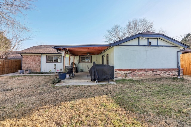 back of property with a patio area, a yard, fence, and brick siding