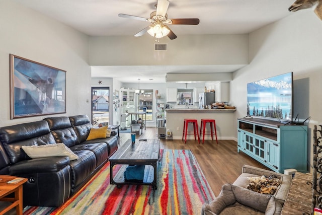 living room with wood finished floors, visible vents, a ceiling fan, vaulted ceiling, and baseboards