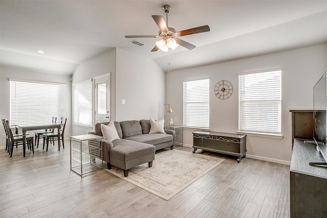 living room with a wealth of natural light, lofted ceiling, light wood-type flooring, and baseboards