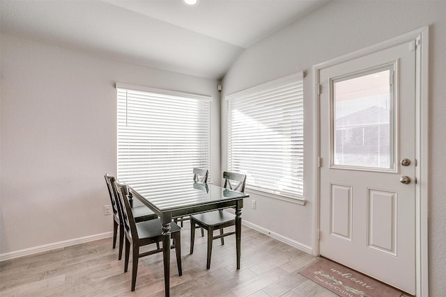 dining space featuring lofted ceiling, light wood finished floors, and baseboards