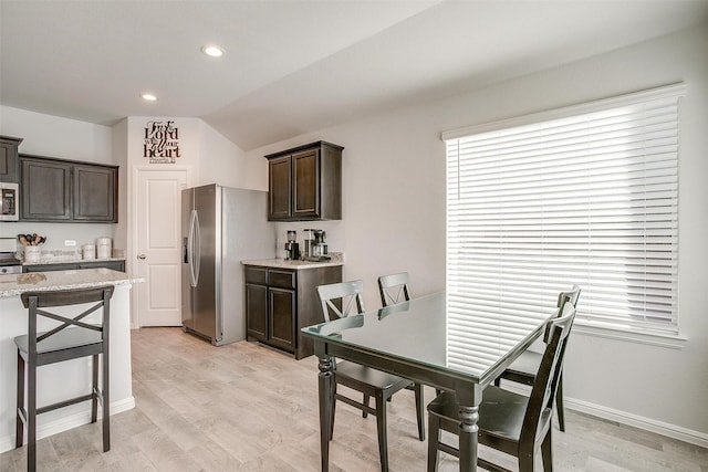 kitchen with recessed lighting, stainless steel appliances, dark brown cabinets, light wood-type flooring, and light stone countertops