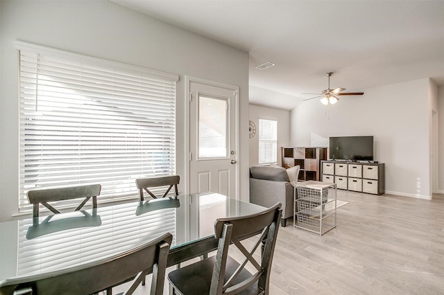 dining area with lofted ceiling, visible vents, baseboards, a ceiling fan, and light wood finished floors