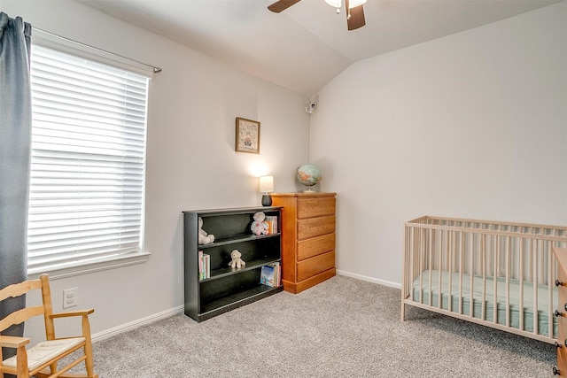 carpeted bedroom featuring lofted ceiling, a nursery area, ceiling fan, and baseboards