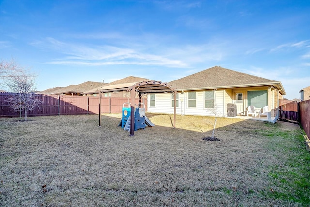 rear view of property featuring a shingled roof, a patio, a fenced backyard, a yard, and a playground