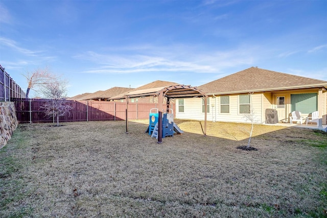 exterior space with a playground, a yard, roof with shingles, a patio area, and a fenced backyard