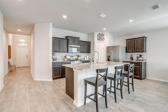 kitchen with visible vents, light wood-style flooring, appliances with stainless steel finishes, a sink, and an island with sink