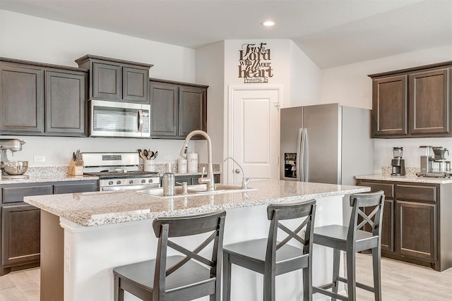 kitchen featuring light wood-type flooring, a breakfast bar area, appliances with stainless steel finishes, and a sink