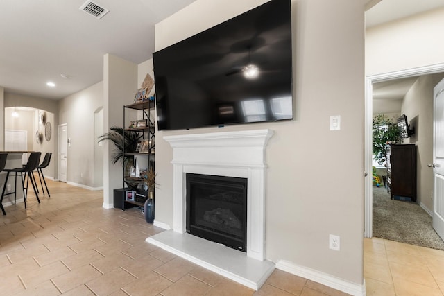 living area featuring visible vents, arched walkways, baseboards, a glass covered fireplace, and light tile patterned flooring