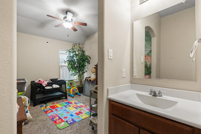 bathroom with lofted ceiling, a textured wall, a ceiling fan, and vanity