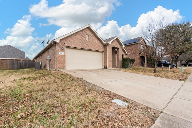 view of front of property with an attached garage, cooling unit, solar panels, brick siding, and concrete driveway