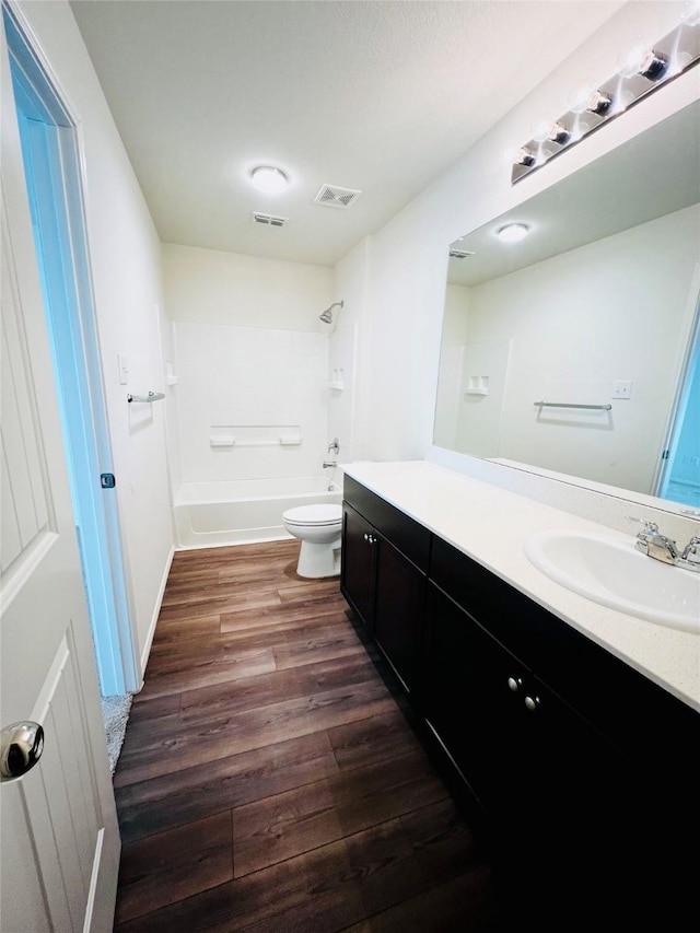 full bath featuring visible vents, toilet, wood finished floors,  shower combination, and vanity