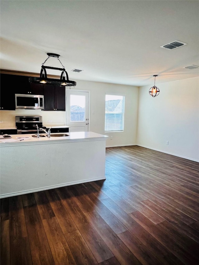 kitchen with dark wood-type flooring, a sink, visible vents, light countertops, and appliances with stainless steel finishes