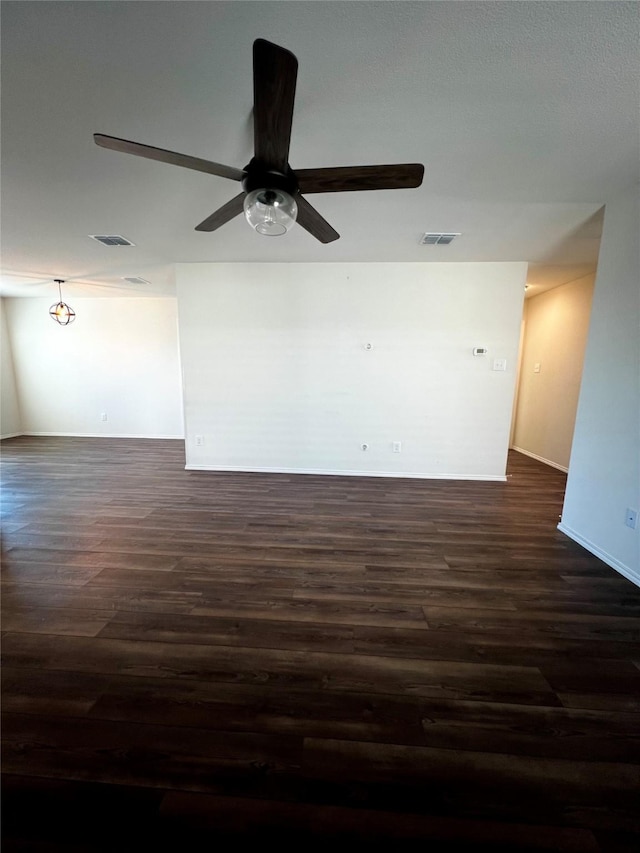 spare room featuring a ceiling fan, visible vents, and dark wood-style flooring