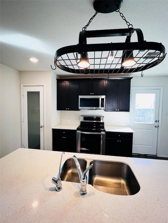 kitchen featuring appliances with stainless steel finishes, a sink, and dark cabinets