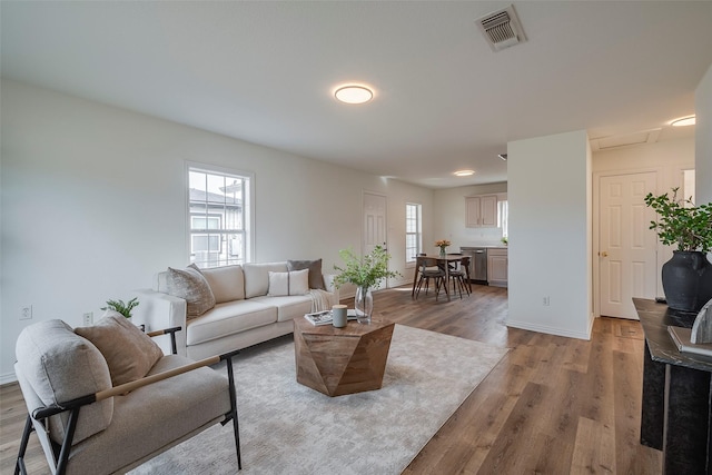 living area with baseboards, visible vents, and wood finished floors