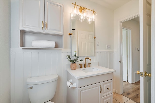 bathroom featuring visible vents, wainscoting, vanity, and toilet