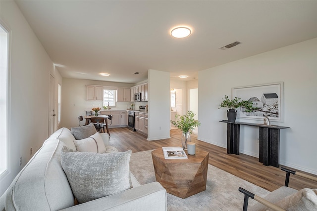 living area featuring baseboards, visible vents, and light wood-style floors