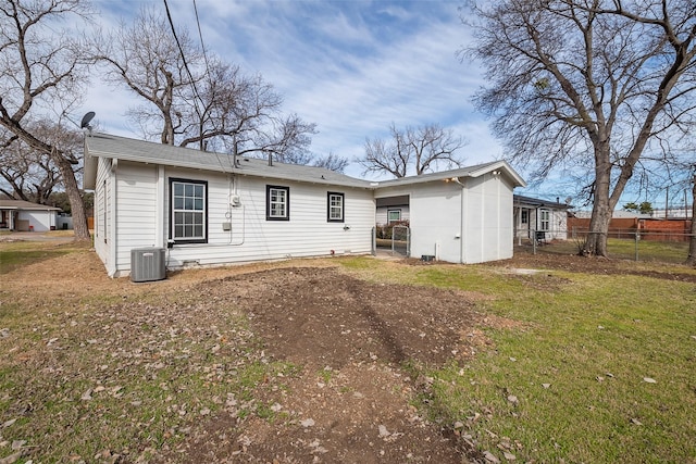 rear view of property featuring a lawn, fence, and central air condition unit