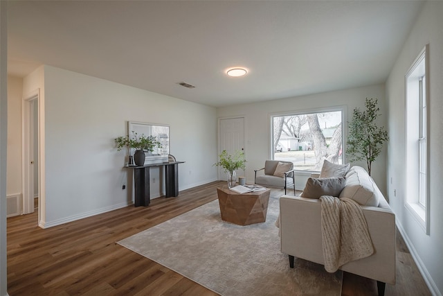 sitting room with baseboards, visible vents, and wood finished floors