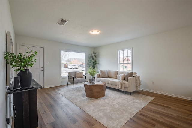 living room with baseboards, visible vents, and wood finished floors