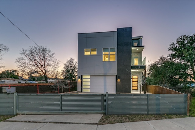 contemporary home featuring an attached garage, a fenced front yard, and a gate