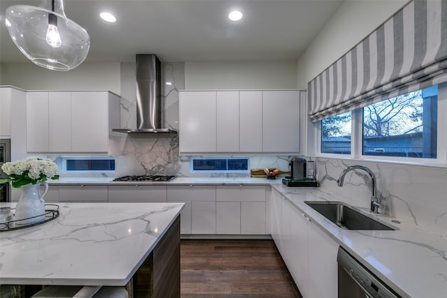 kitchen with appliances with stainless steel finishes, a sink, wall chimney range hood, and modern cabinets