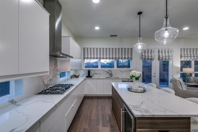 kitchen featuring stainless steel gas stovetop, a sink, wall chimney range hood, modern cabinets, and beverage cooler