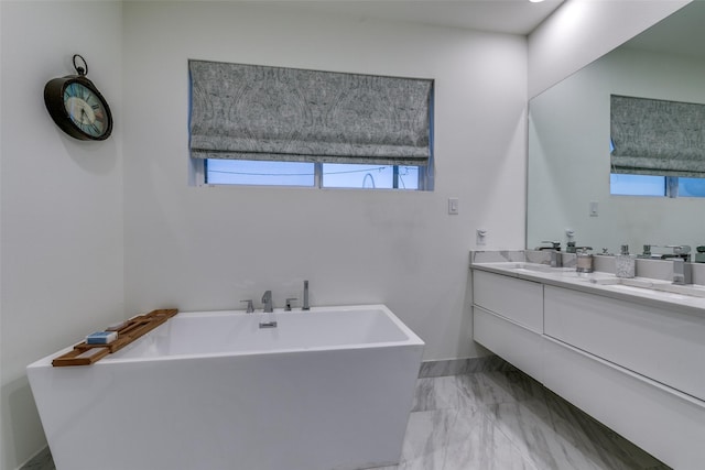 full bathroom featuring marble finish floor, a freestanding bath, and vanity