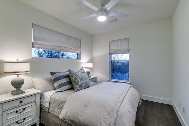 bedroom with a ceiling fan, visible vents, dark wood finished floors, and baseboards