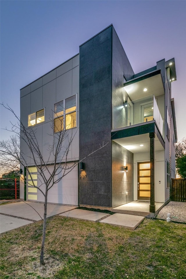 modern home featuring fence, driveway, an attached garage, and stucco siding