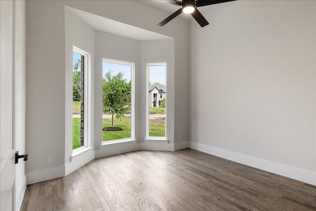 unfurnished room with ceiling fan, wood finished floors, and baseboards