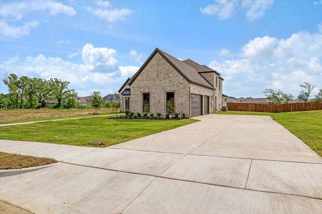 french country style house with brick siding, driveway, a front lawn, and fence