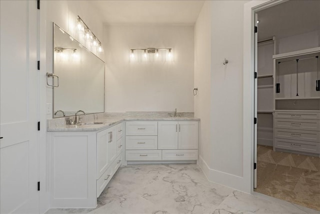 full bathroom featuring marble finish floor, a sink, baseboards, and double vanity