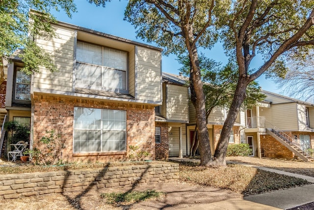 view of front of home featuring brick siding and stairway