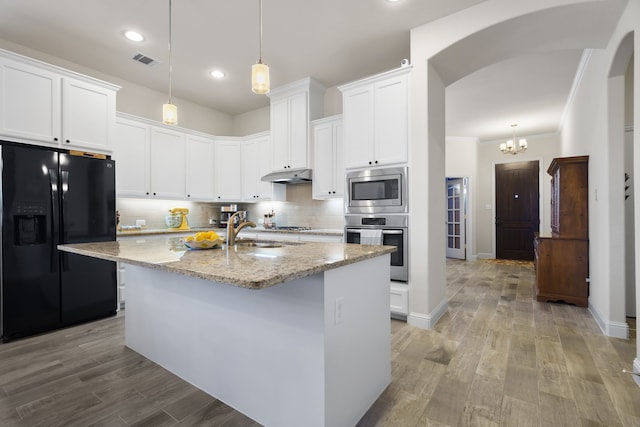 kitchen featuring arched walkways, stainless steel appliances, a sink, visible vents, and decorative backsplash