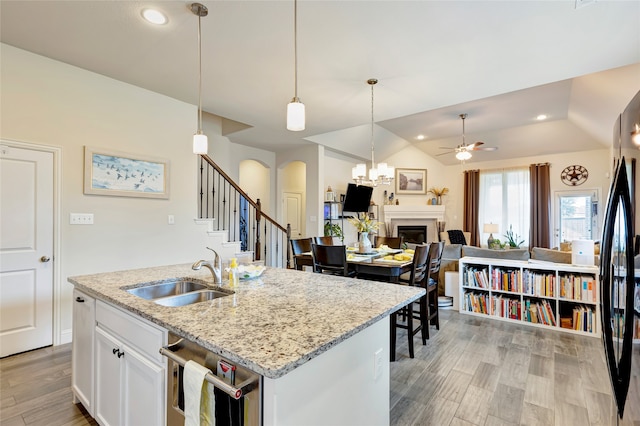 2101 Bishop Barrel Ln, Wylie, TX 75098 - kitchen with a sink, arched walkways, light wood-type flooring, a ceiling fan, and white cabinets