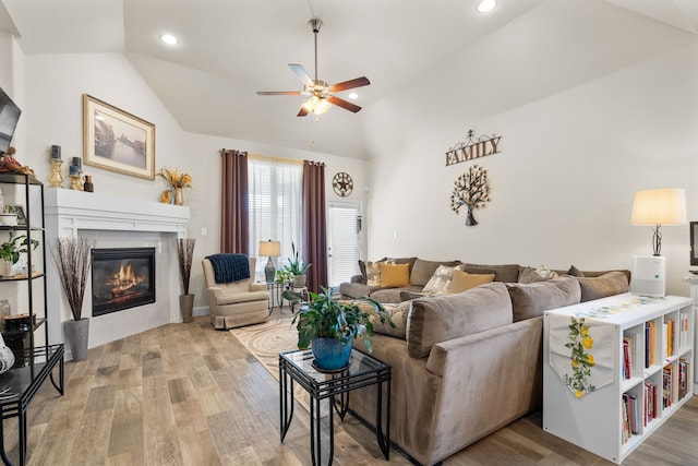 living room featuring light wood-type flooring, a glass covered fireplace, lofted ceiling, and recessed lighting