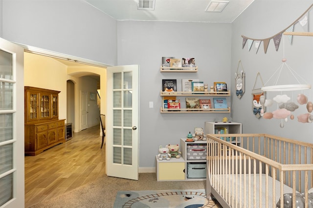 2101 Bishop Barrel Ln, Wylie, TX 75098 - bedroom with a crib, arched walkways, french doors, wood finished floors, and baseboards