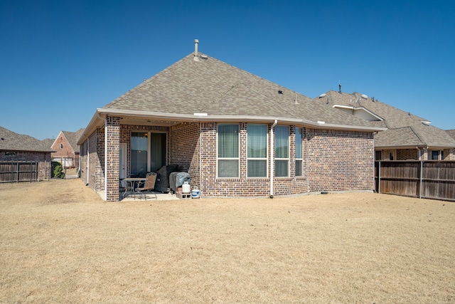 rear view of house with brick siding, a shingled roof, and fence private yard