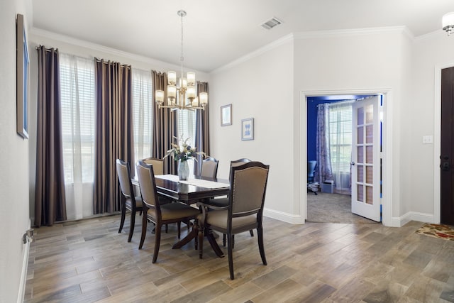 dining area with a notable chandelier, visible vents, baseboards, light wood-style floors, and crown molding