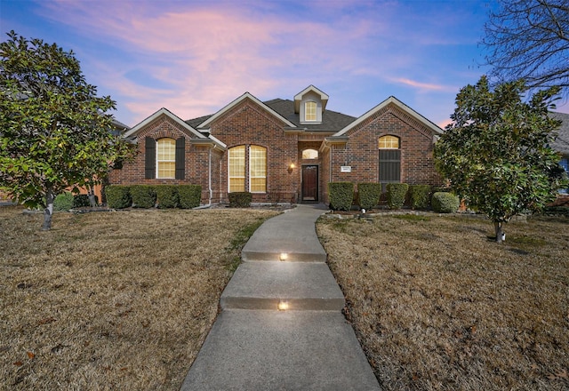 view of front of property with brick siding and a lawn