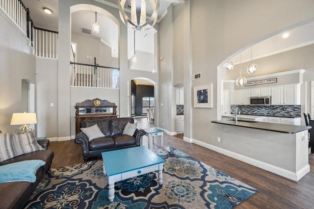 living room with arched walkways, dark wood-style floors, visible vents, and baseboards