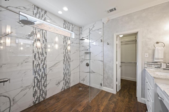 bathroom featuring a marble finish shower, visible vents, ornamental molding, vanity, and wood finished floors