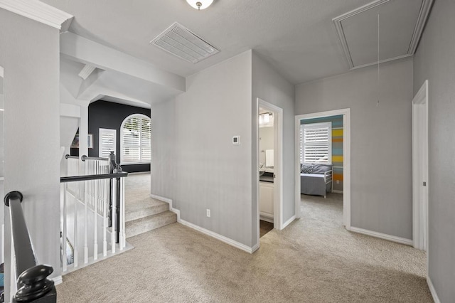 hallway featuring carpet floors, visible vents, an upstairs landing, baseboards, and attic access