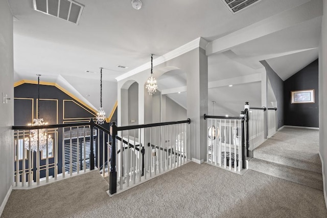 hall featuring carpet floors, lofted ceiling, visible vents, and an inviting chandelier