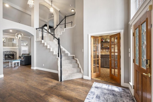 foyer entrance with stairs, a fireplace, wood finished floors, and baseboards