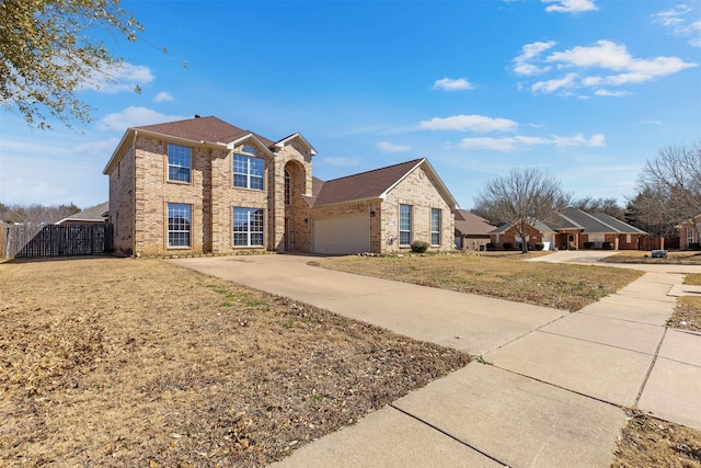 traditional home with brick siding, driveway, an attached garage, and fence