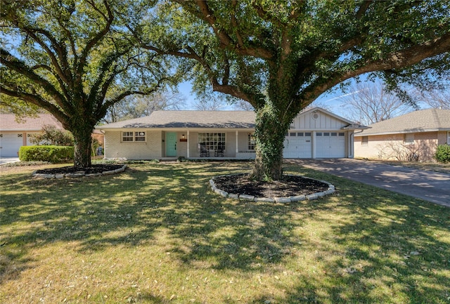 ranch-style home with brick siding, an attached garage, board and batten siding, a front yard, and driveway